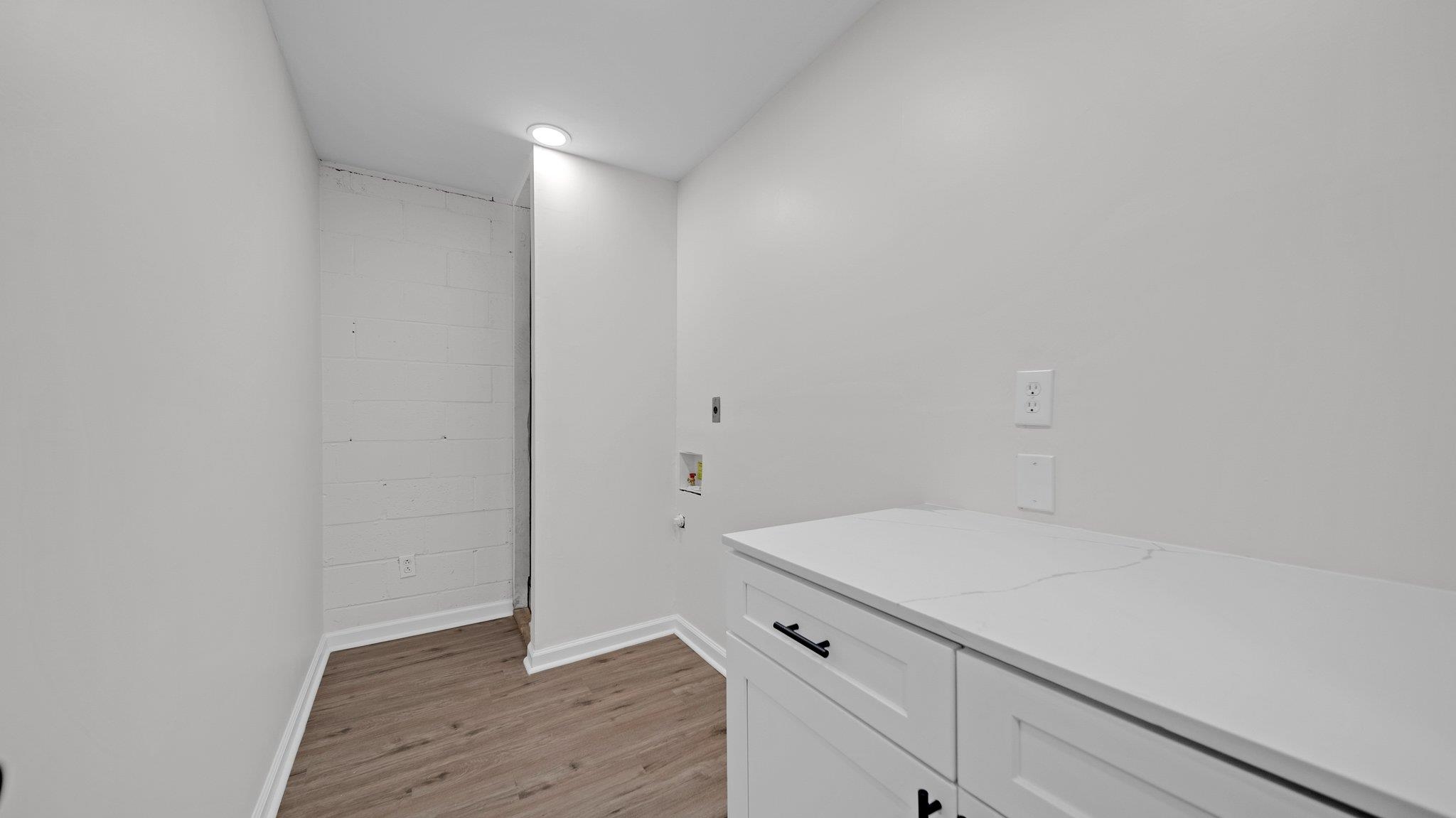 Clothes washing area with hookup for a washing machine and light wood-type flooring