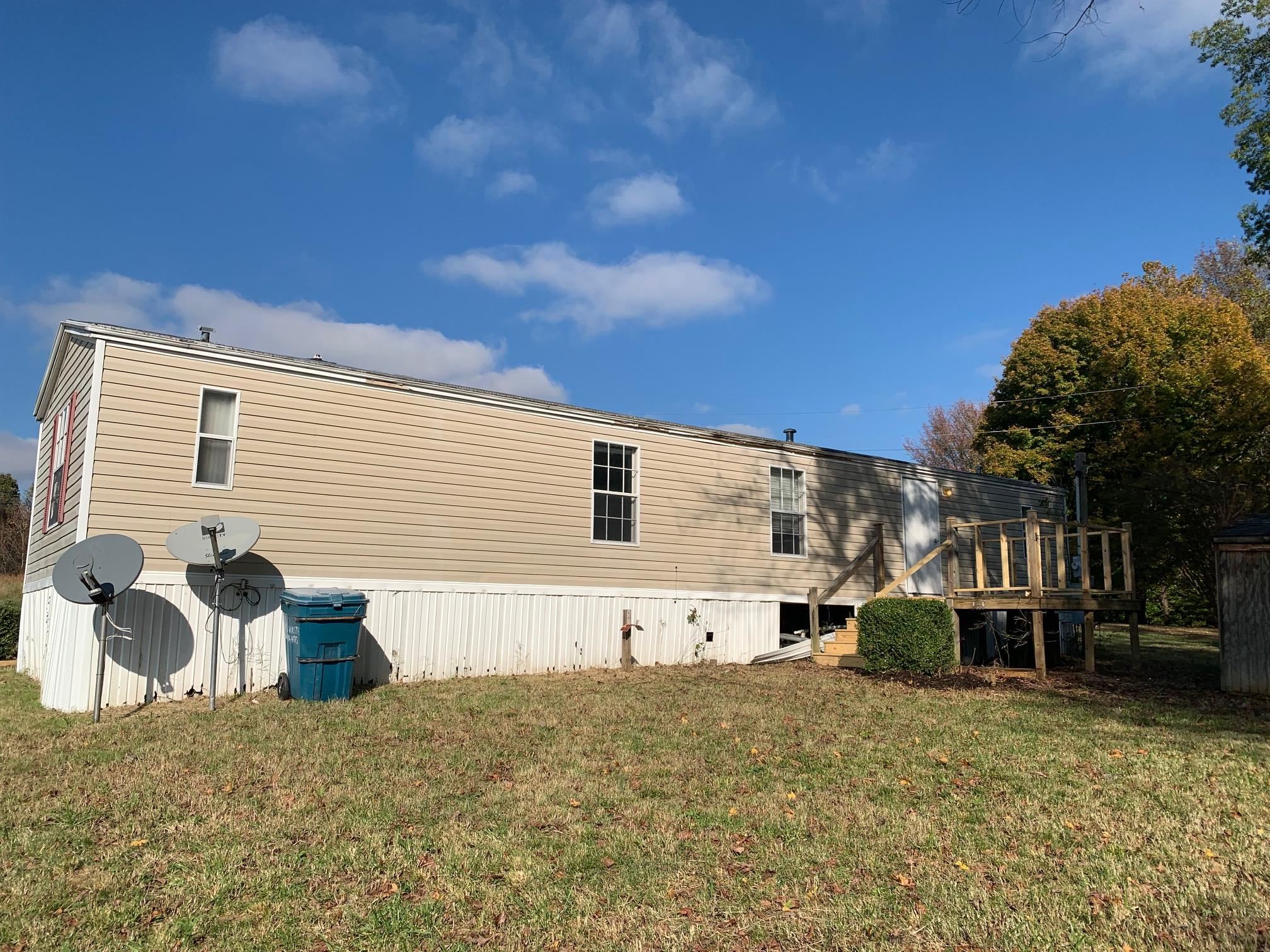 Back of property featuring a lawn and a deck