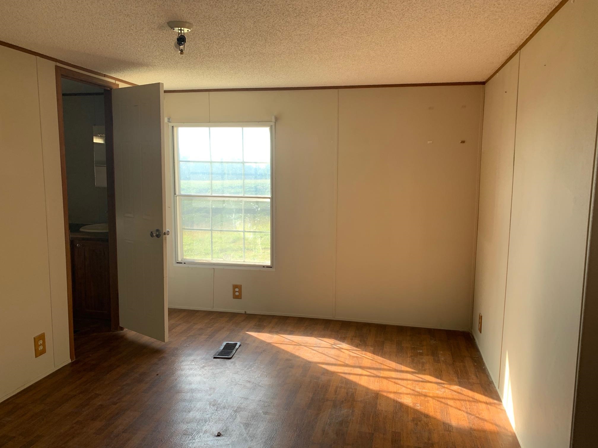 Empty room with a textured ceiling and dark hardwood / wood-style floors