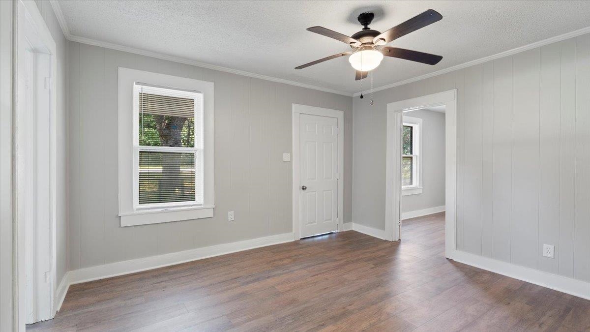 Empty room with plenty of natural light, dark hardwood / wood-style floors, a textured ceiling, and ceiling fan