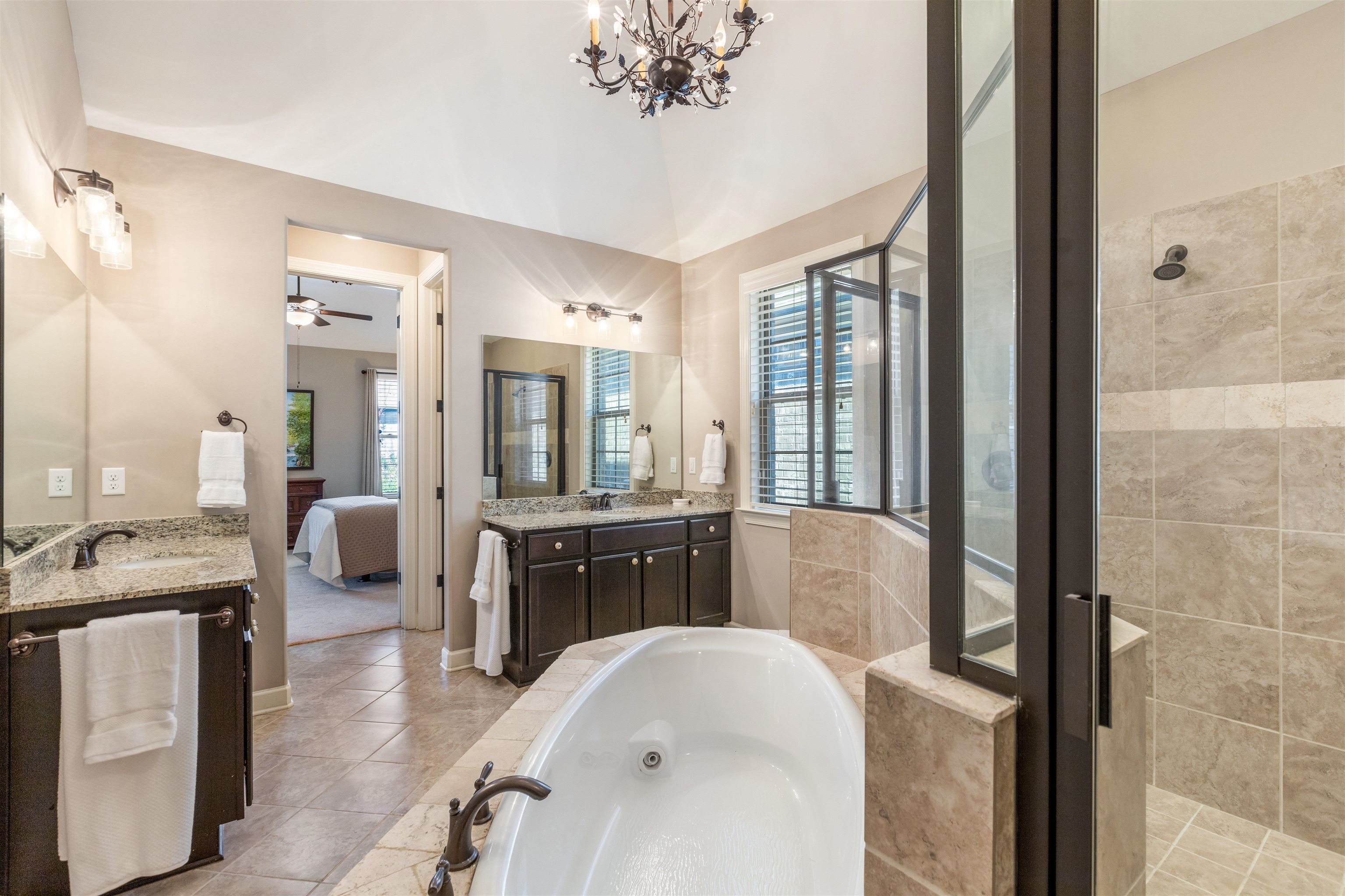 Bathroom featuring ceiling fan with notable chandelier, shower with separate bathtub, vanity, and tile patterned floors