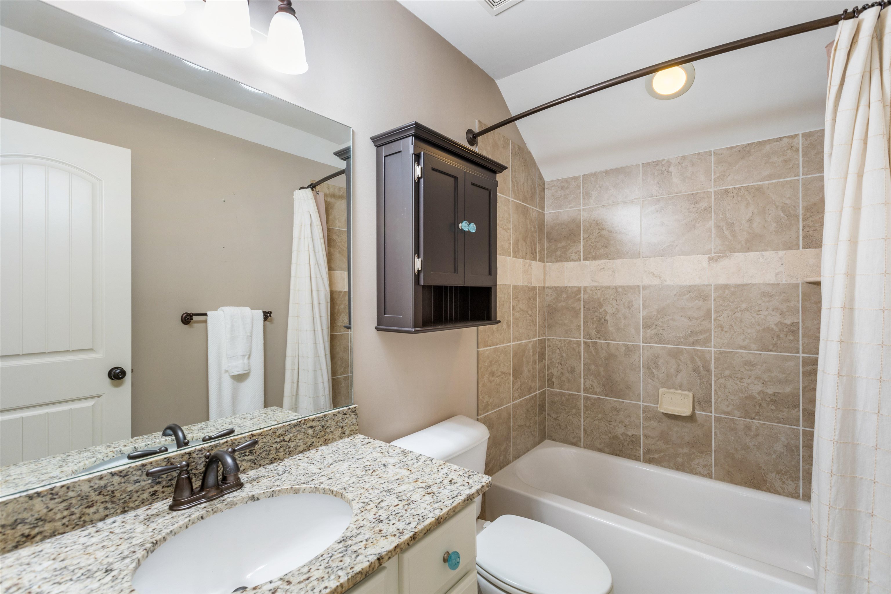 Full bathroom with shower / bathtub combination with curtain, vanity, vaulted ceiling, and toilet