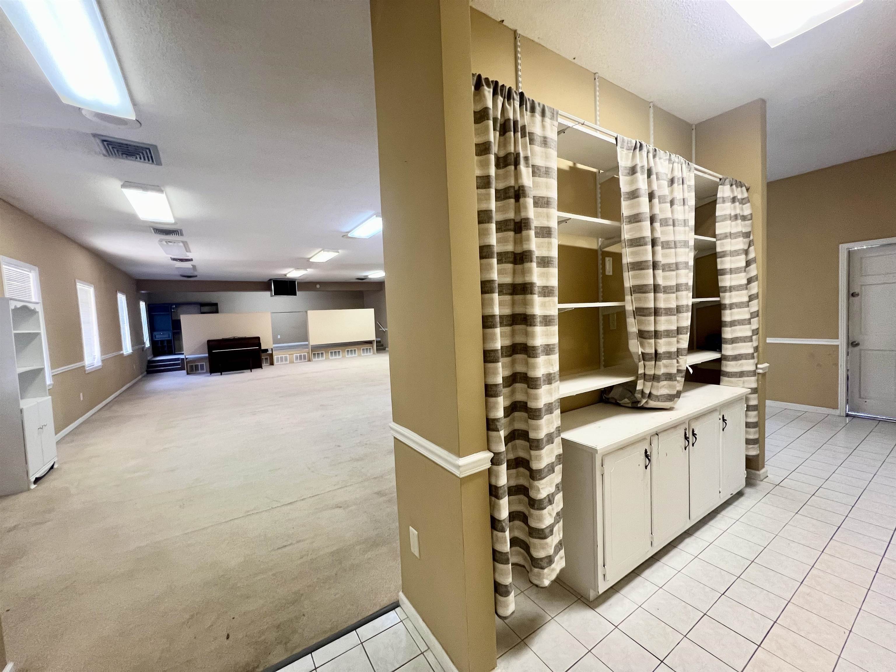 Interior space featuring white cabinets, a textured ceiling, and light colored carpet