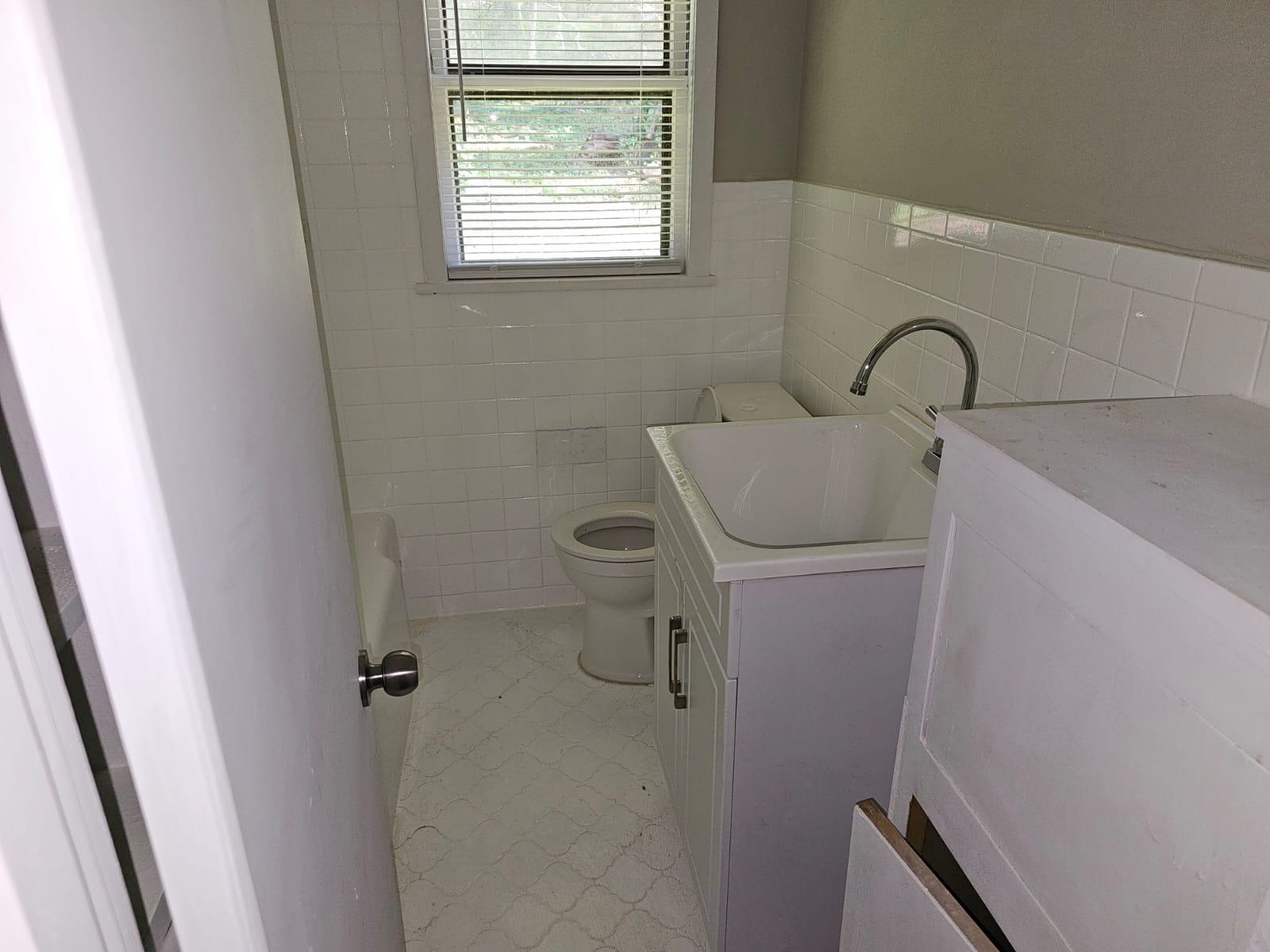 Bathroom featuring tile walls, vanity, toilet, and tile patterned flooring