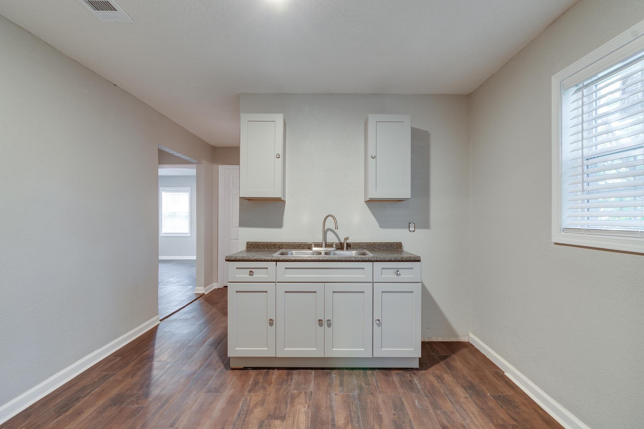 Kitchen featuring white cabinets, dark hardwood / wood-style floors, sink, and a wealth of natural light