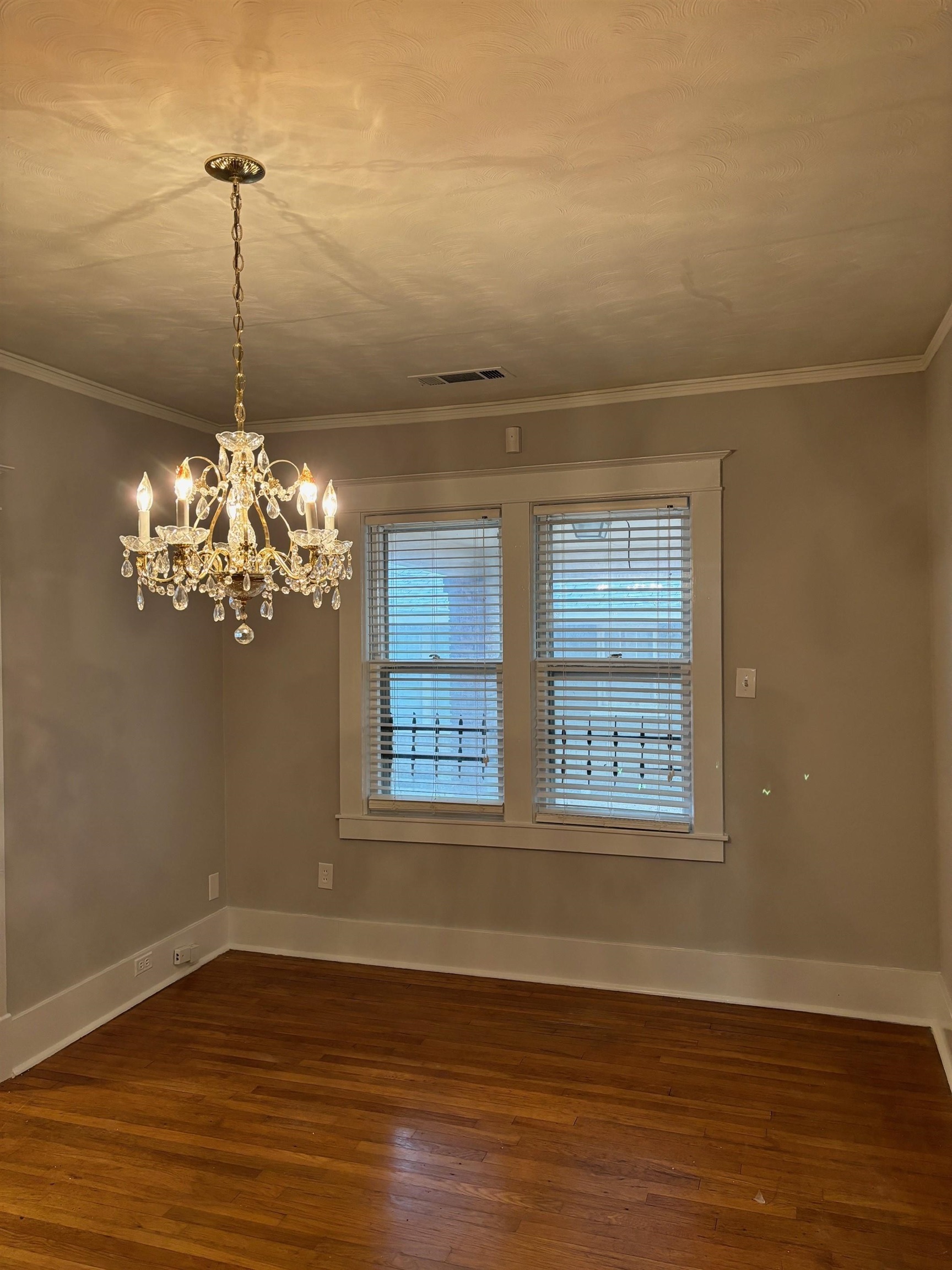 Unfurnished room featuring a chandelier, dark hardwood / wood-style floors, and ornamental molding