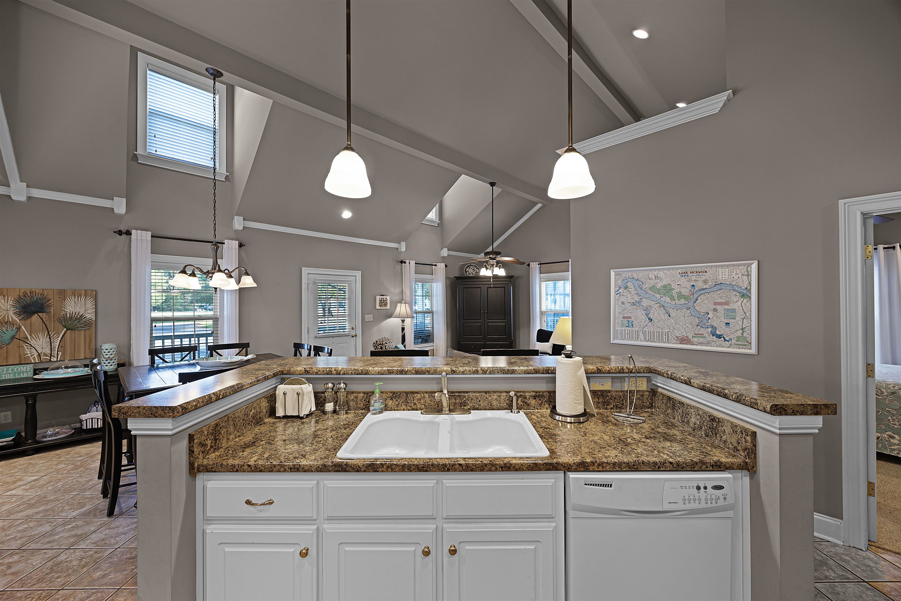 Kitchen featuring pendant lighting, dishwasher, white cabinetry, and sink