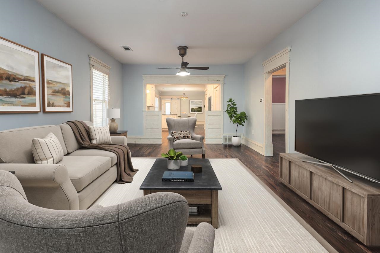 Living room featuring dark wood-type flooring and ceiling fan with notable chandelier