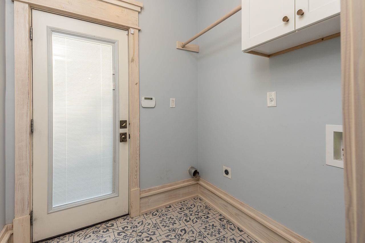 Washroom featuring light tile patterned floors, cabinets, and hookup for an electric dryer