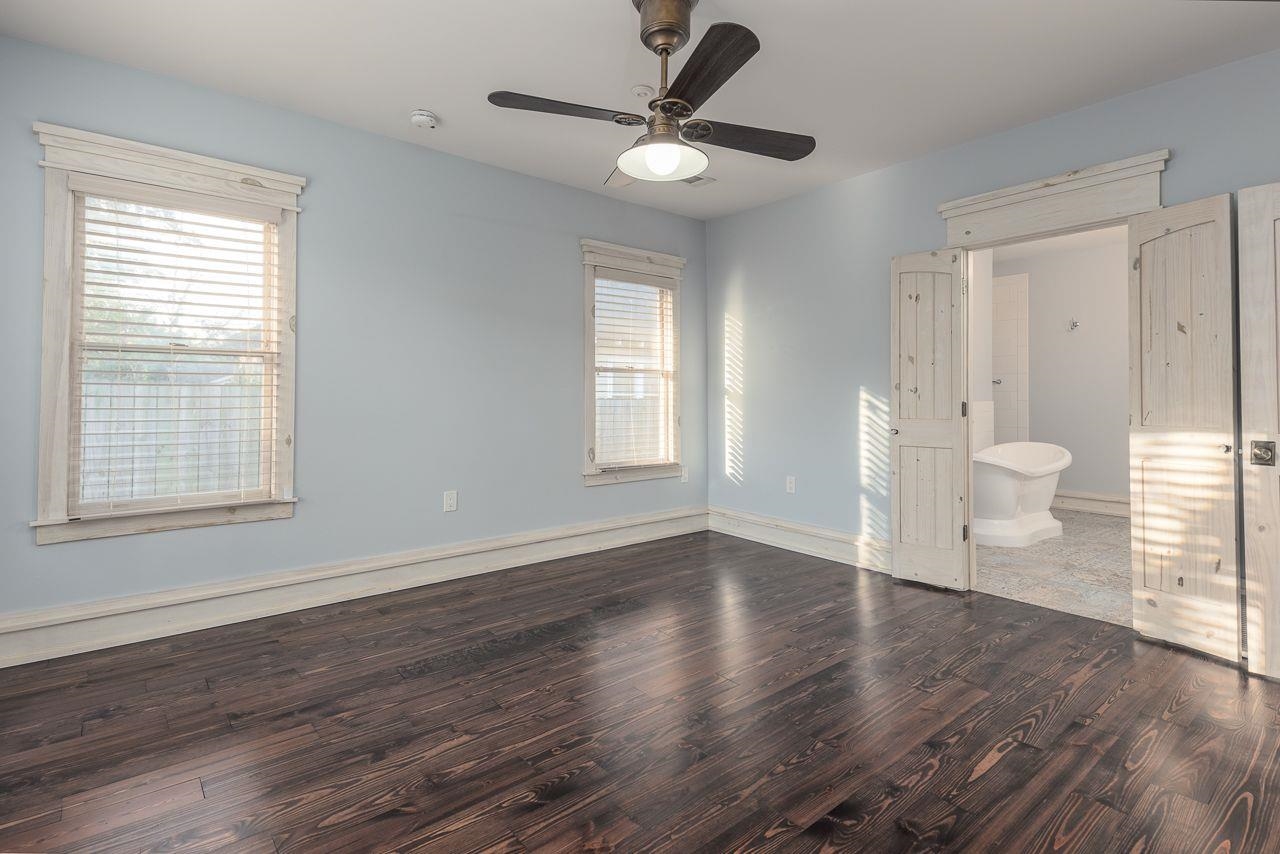 Unfurnished bedroom with ceiling fan, dark wood-type flooring, and ensuite bath