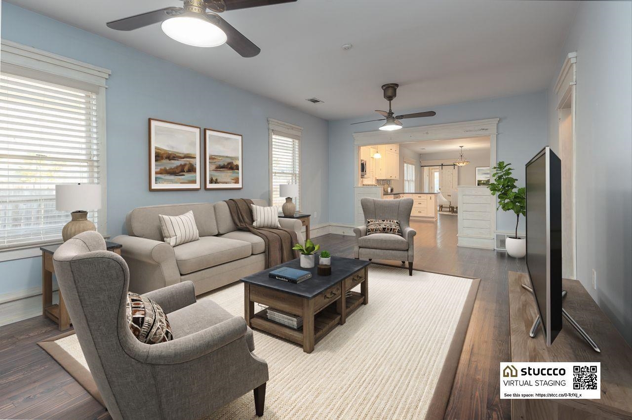 Living room with ceiling fan with notable chandelier and hardwood / wood-style flooring