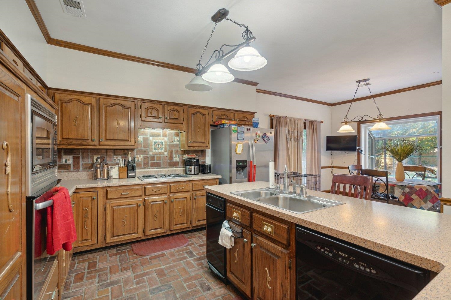 Kitchen with decorative light fixtures, stainless steel appliances, ornamental molding, and sink