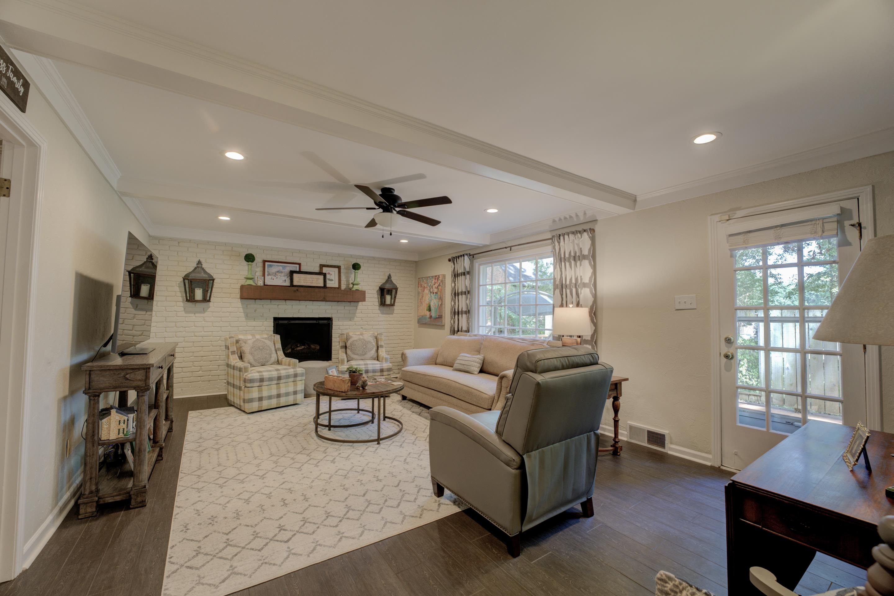 Enjoy the charm of this spacious great room featuring a wood-beamed ceiling, recessed lighting, cooling ceiling fan, hardwood floors, and a cozy fireplace—perfect for relaxation and entertaining.