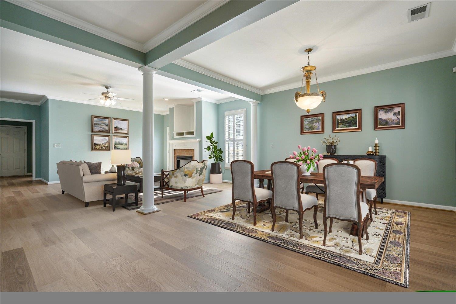 Dining space featuring ornate columns, crown molding, ceiling fan, and light wood-type flooring