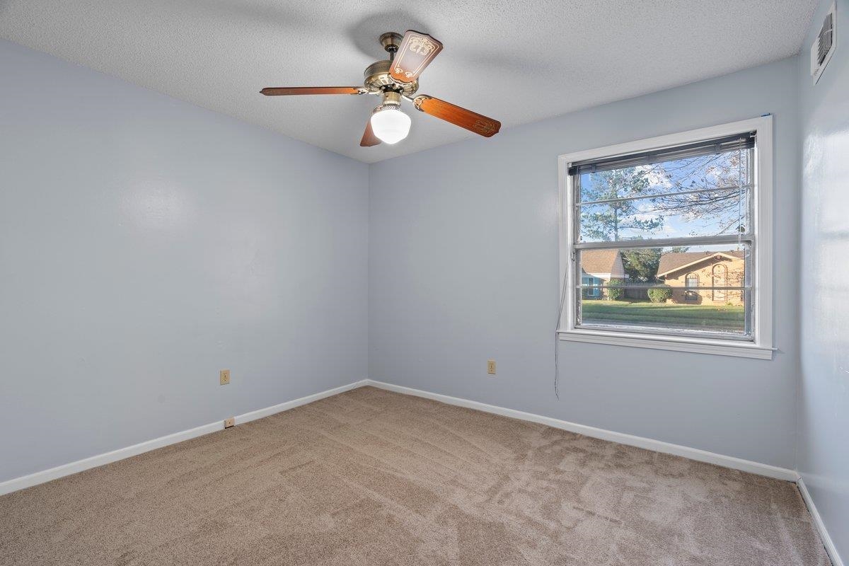 Empty room with carpet flooring, ceiling fan, and a textured ceiling