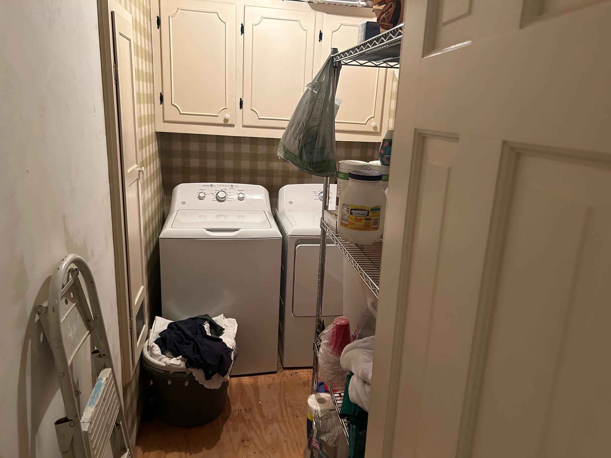 Clothes washing area featuring cabinets, washing machine and dryer, and light hardwood / wood-style floors