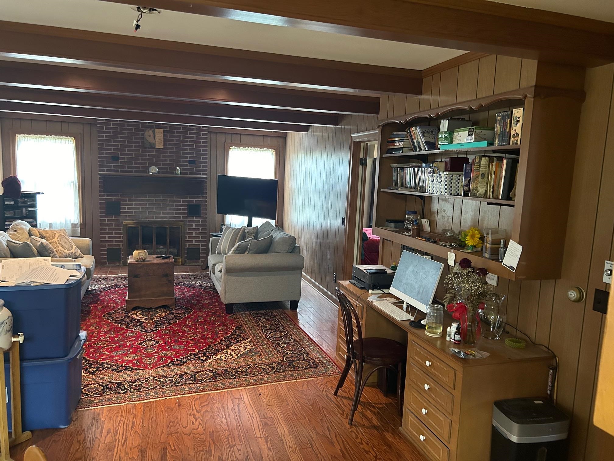 Office area featuring beam ceiling, wood-type flooring, a wealth of natural light, and a brick fireplace