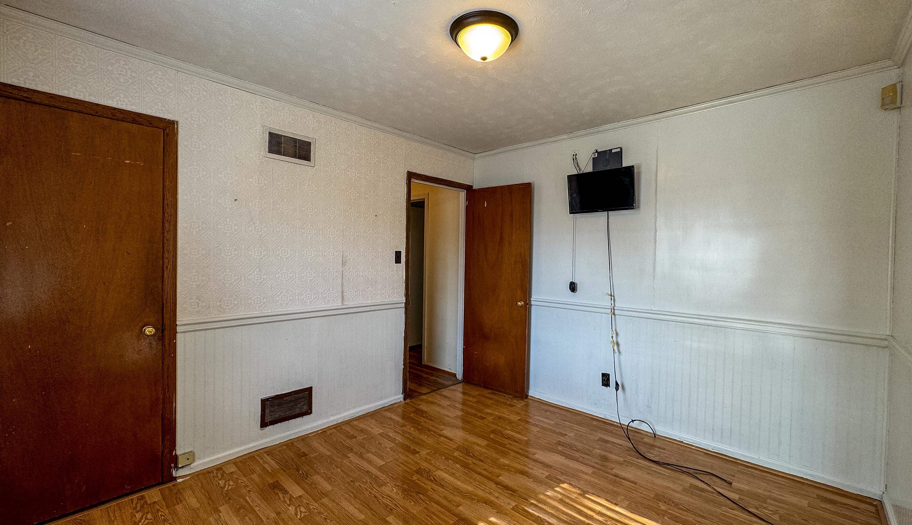 Unfurnished bedroom with wood-type flooring, a textured ceiling, and ornamental molding