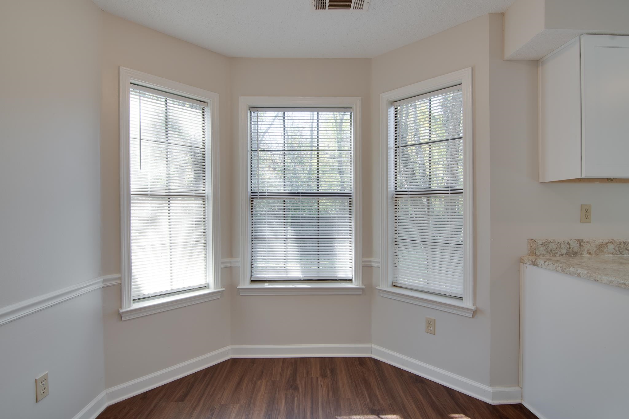 Unfurnished dining area featuring dark wood-type flooring and a healthy amount of sunlight