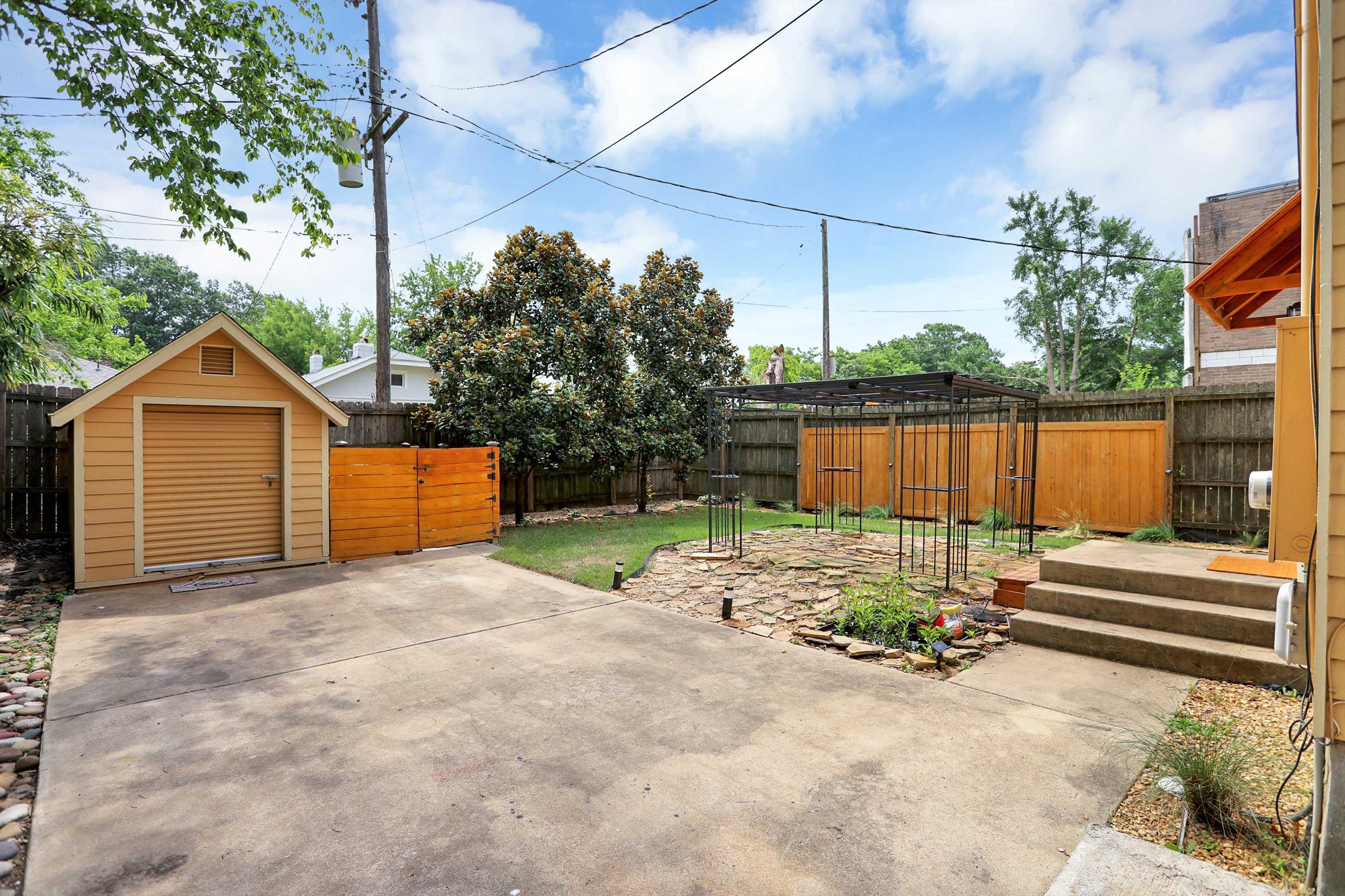 Back parking area with storage building, patio and green space
