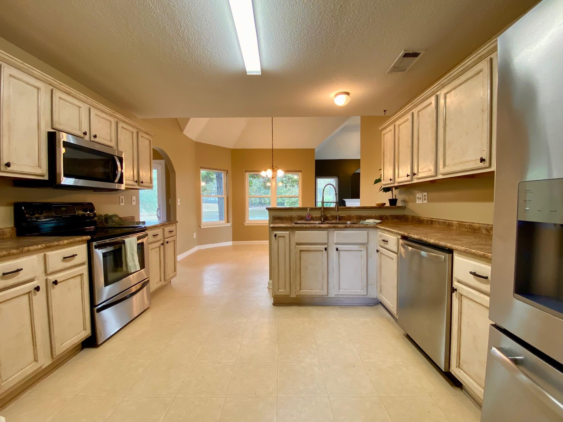 Kitchen with an inviting chandelier, sink, appliances with stainless steel finishes, decorative light fixtures, and kitchen peninsula