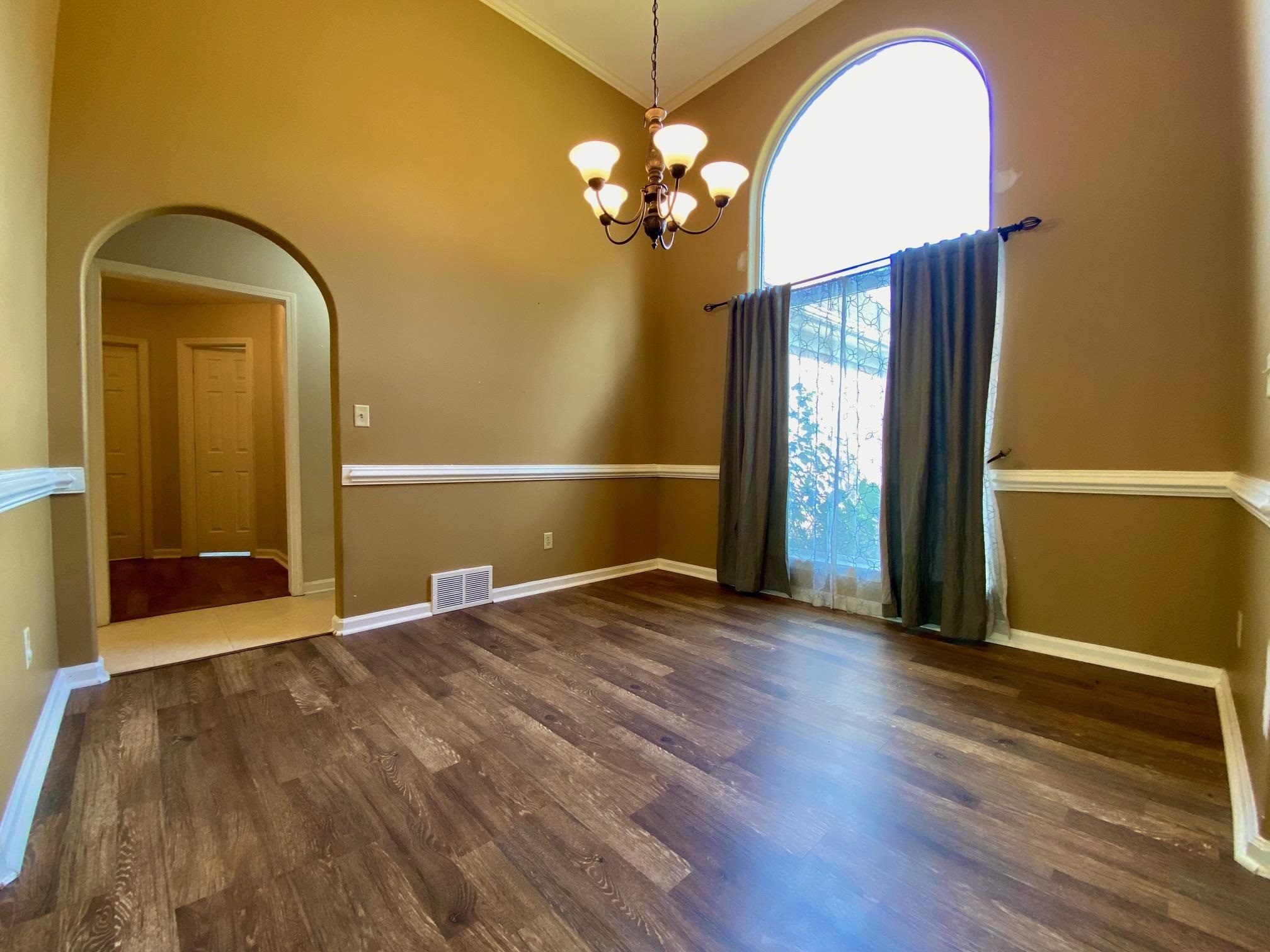 Empty room featuring a notable chandelier, dark hardwood / wood-style floors, and high vaulted ceiling