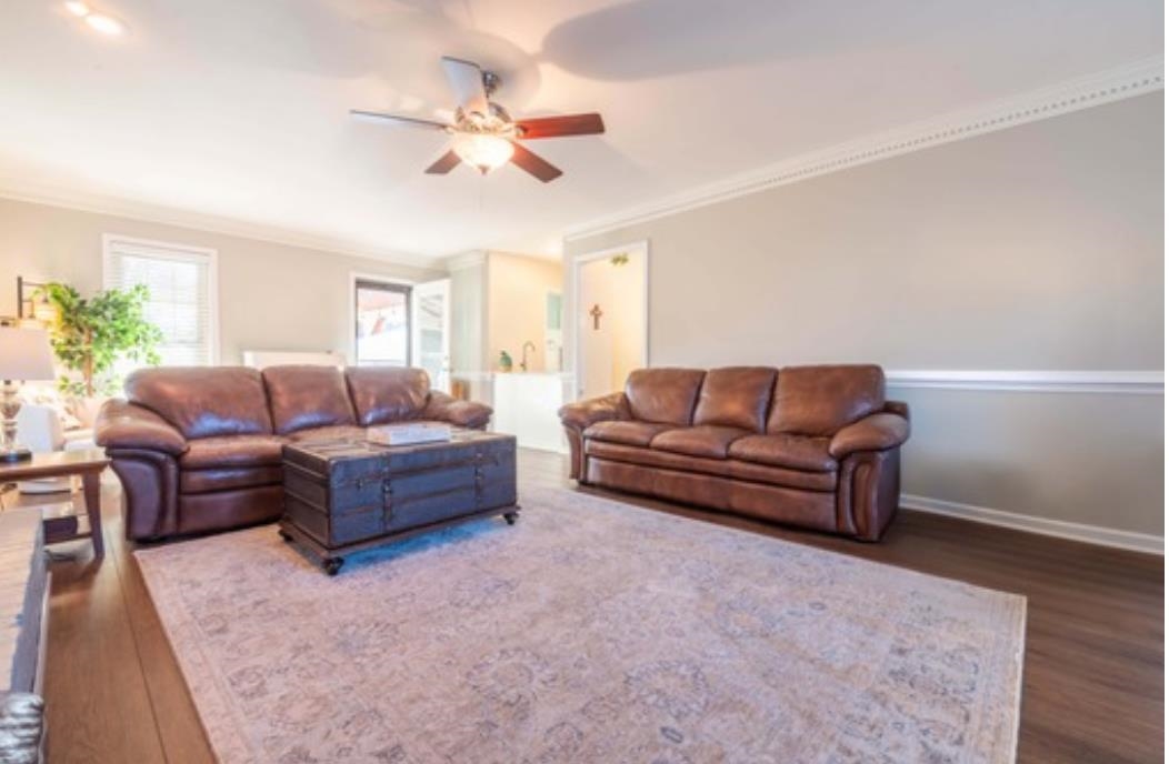 Living room with dark hardwood / wood-style floors, ceiling fan, and ornamental molding