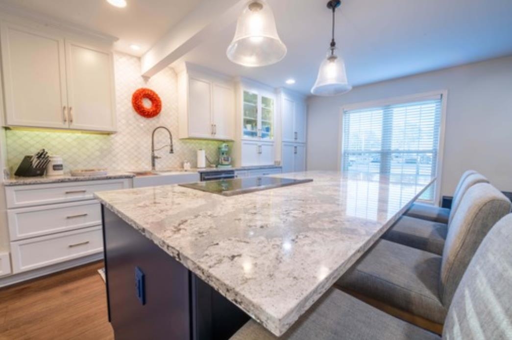 Kitchen featuring a center island, tasteful backsplash, wood-type flooring, decorative light fixtures, and white cabinets