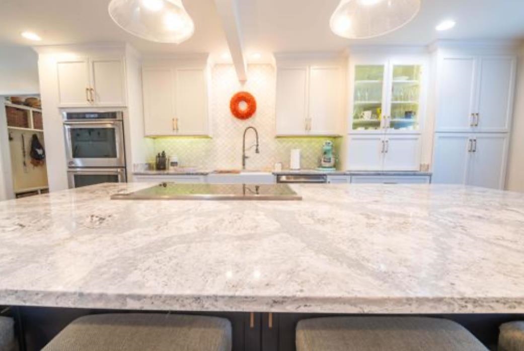 Kitchen with beam ceiling, stainless steel double oven, white cabinetry, and hanging light fixtures