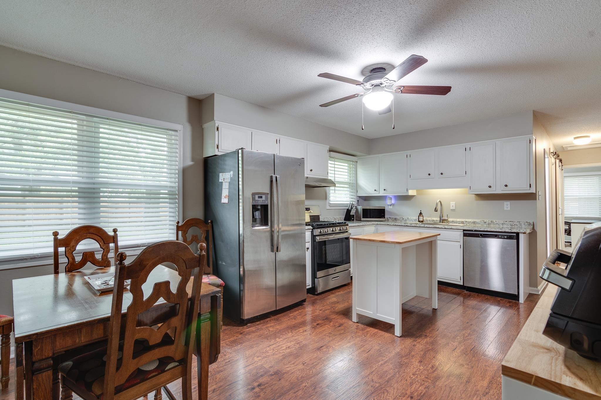 Kitchen featuring sink, dark hardwood / wood-style floors, a textured ceiling, white cabinets, and appliances with stainless steel finishes