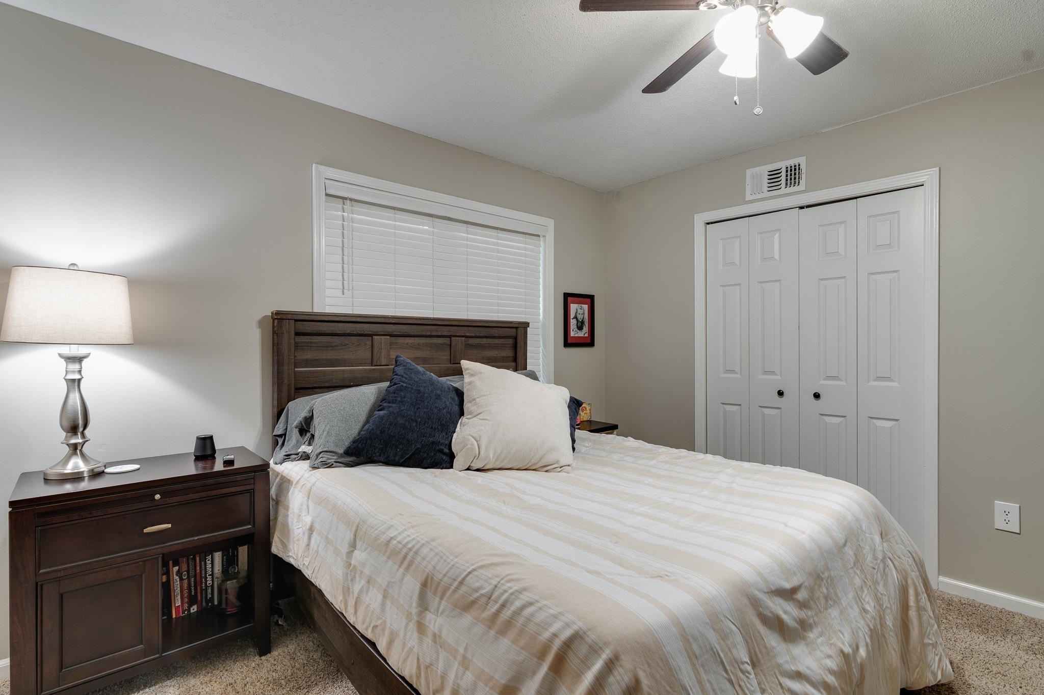 Carpeted bedroom with ceiling fan and a closet