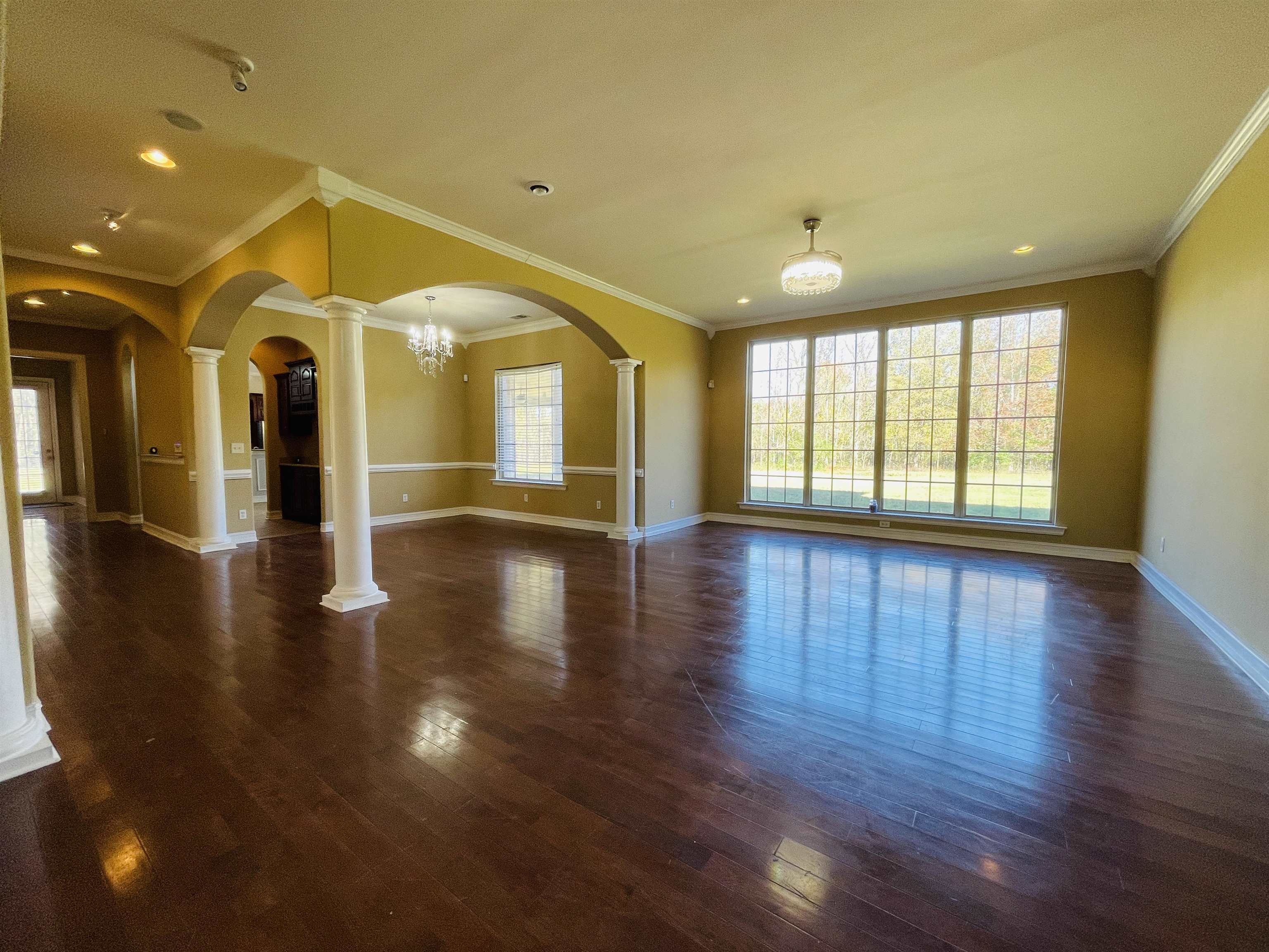 Spare room featuring ornate columns, crown molding, a chandelier, and dark hardwood / wood-style floors