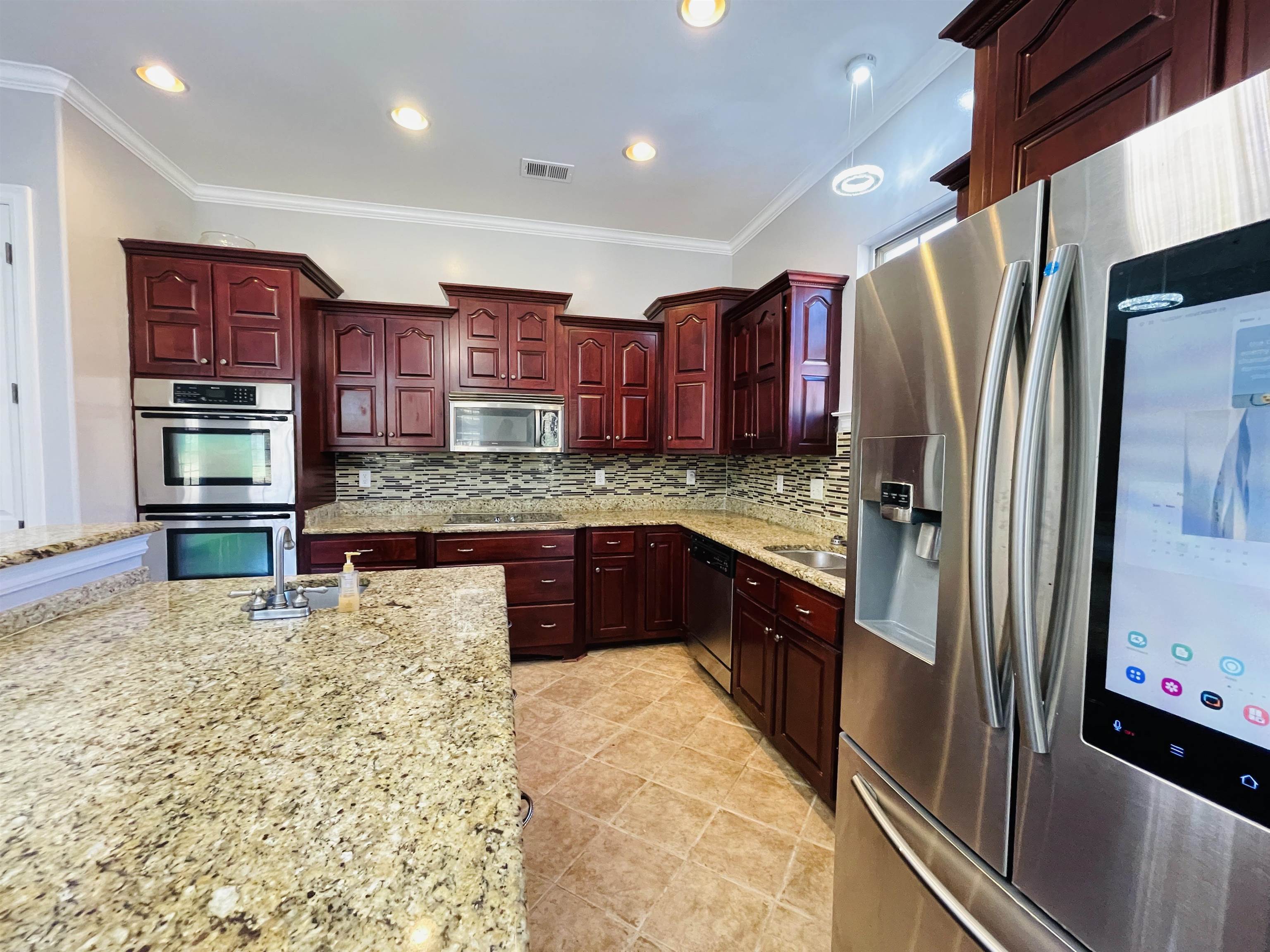 Kitchen with tasteful backsplash, crown molding, sink, and appliances with stainless steel finishes