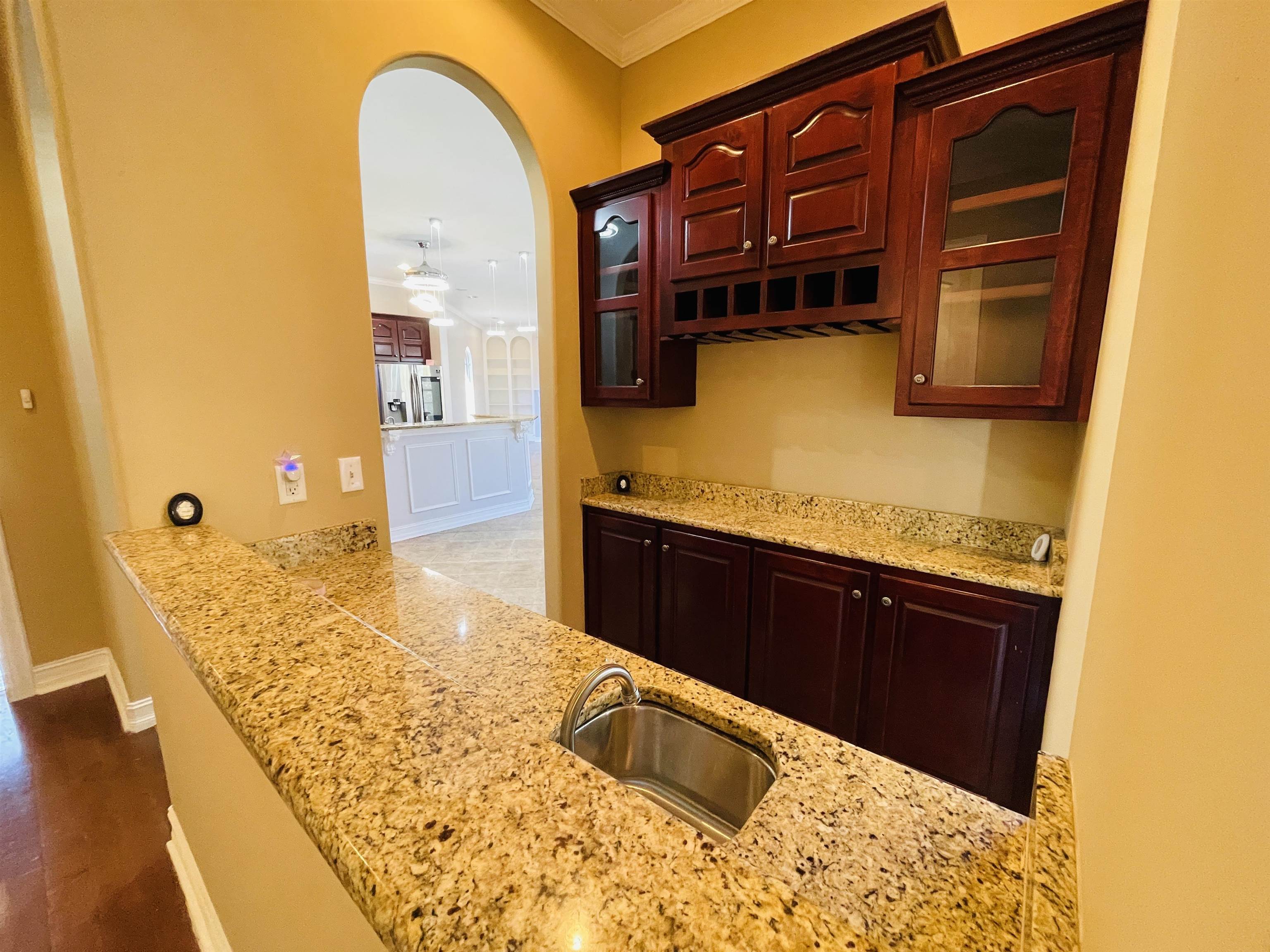 Kitchen featuring stainless steel fridge with ice dispenser, light stone countertops, dark hardwood / wood-style flooring, and ornamental molding