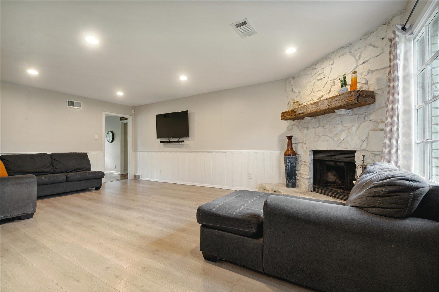 Living room featuring plenty of natural light, a stone fireplace, and light hardwood / wood-style flooring