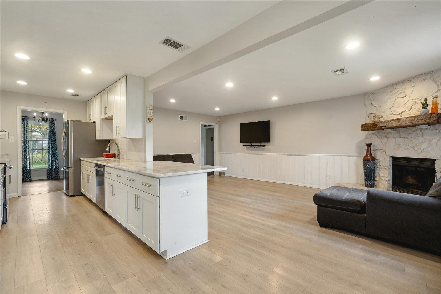 Kitchen featuring white cabinetry, sink, light hardwood / wood-style flooring, a fireplace, and appliances with stainless steel finishes