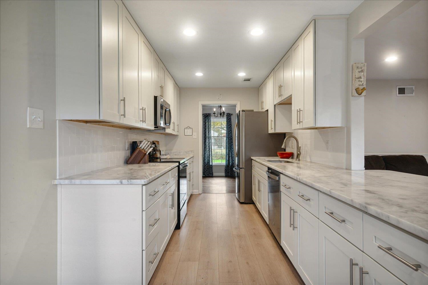 Kitchen featuring white cabinets, appliances with stainless steel finishes, light hardwood / wood-style floors, and sink