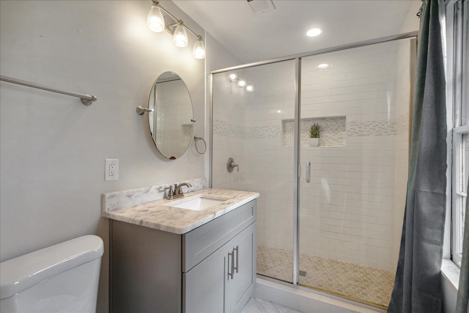 Bathroom featuring vanity, toilet, and a shower with door