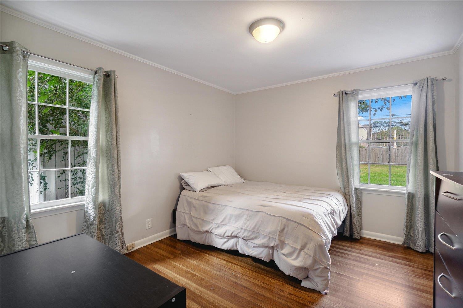 Bedroom featuring multiple windows, dark hardwood / wood-style floors, and ornamental molding