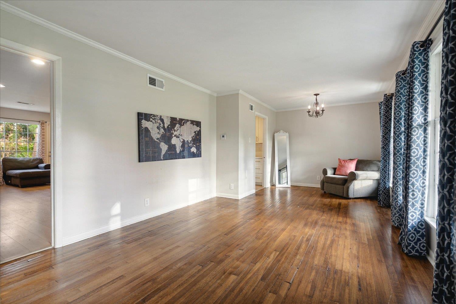 Spare room featuring dark hardwood / wood-style floors, crown molding, and a notable chandelier
