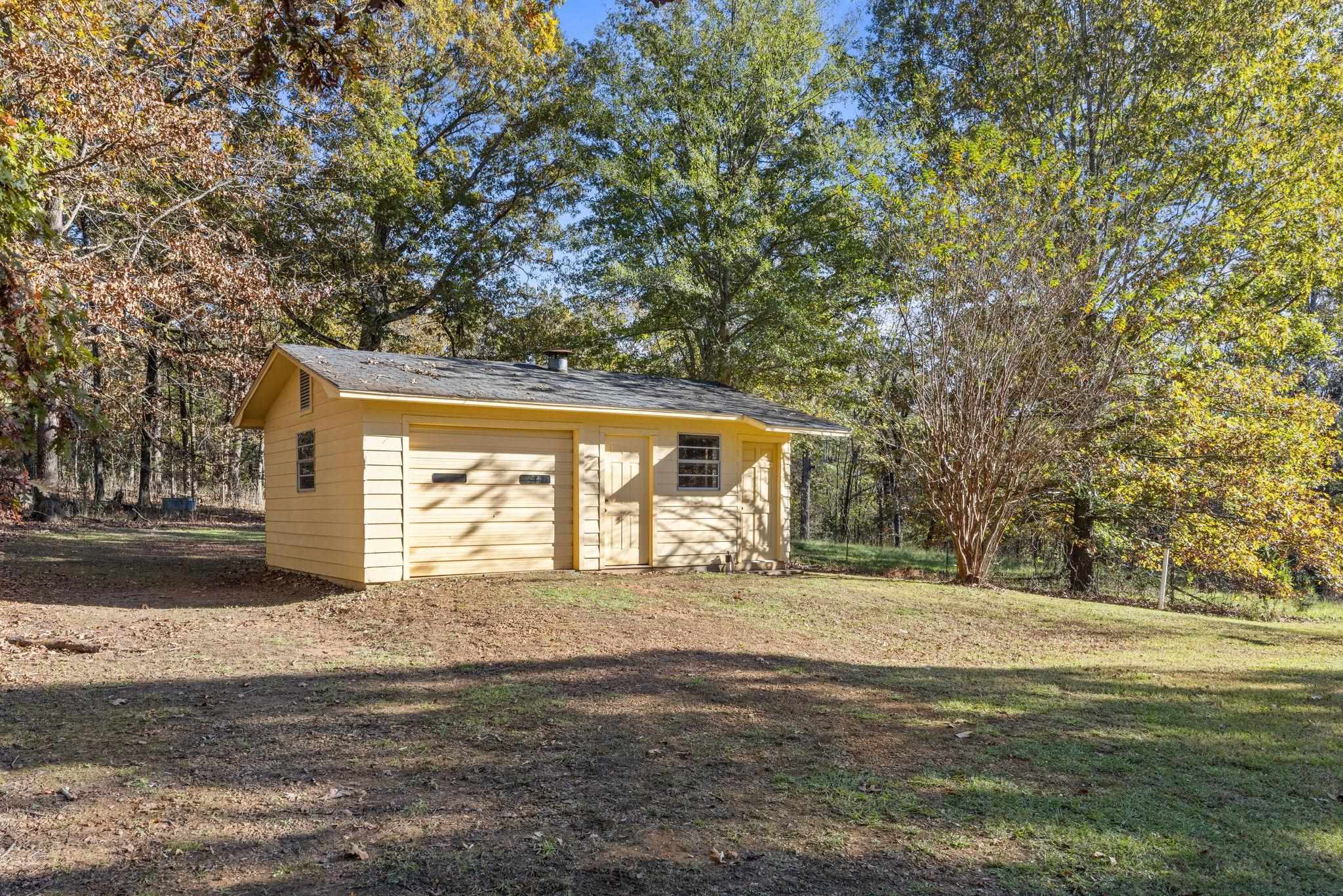 View of outbuilding featuring a lawn and a garage