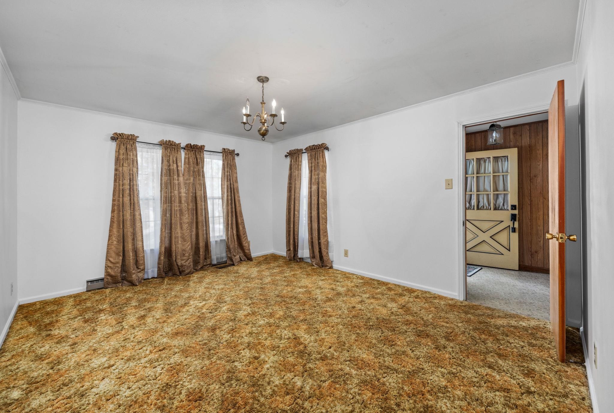 Carpeted spare room with crown molding and a chandelier