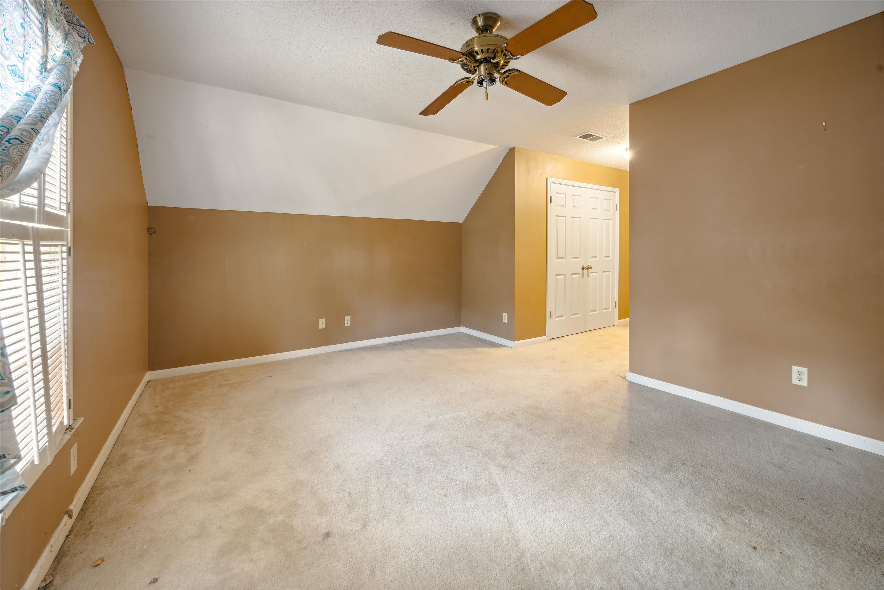 Additional living space with lofted ceiling, light colored carpet, ceiling fan, and a healthy amount of sunlight