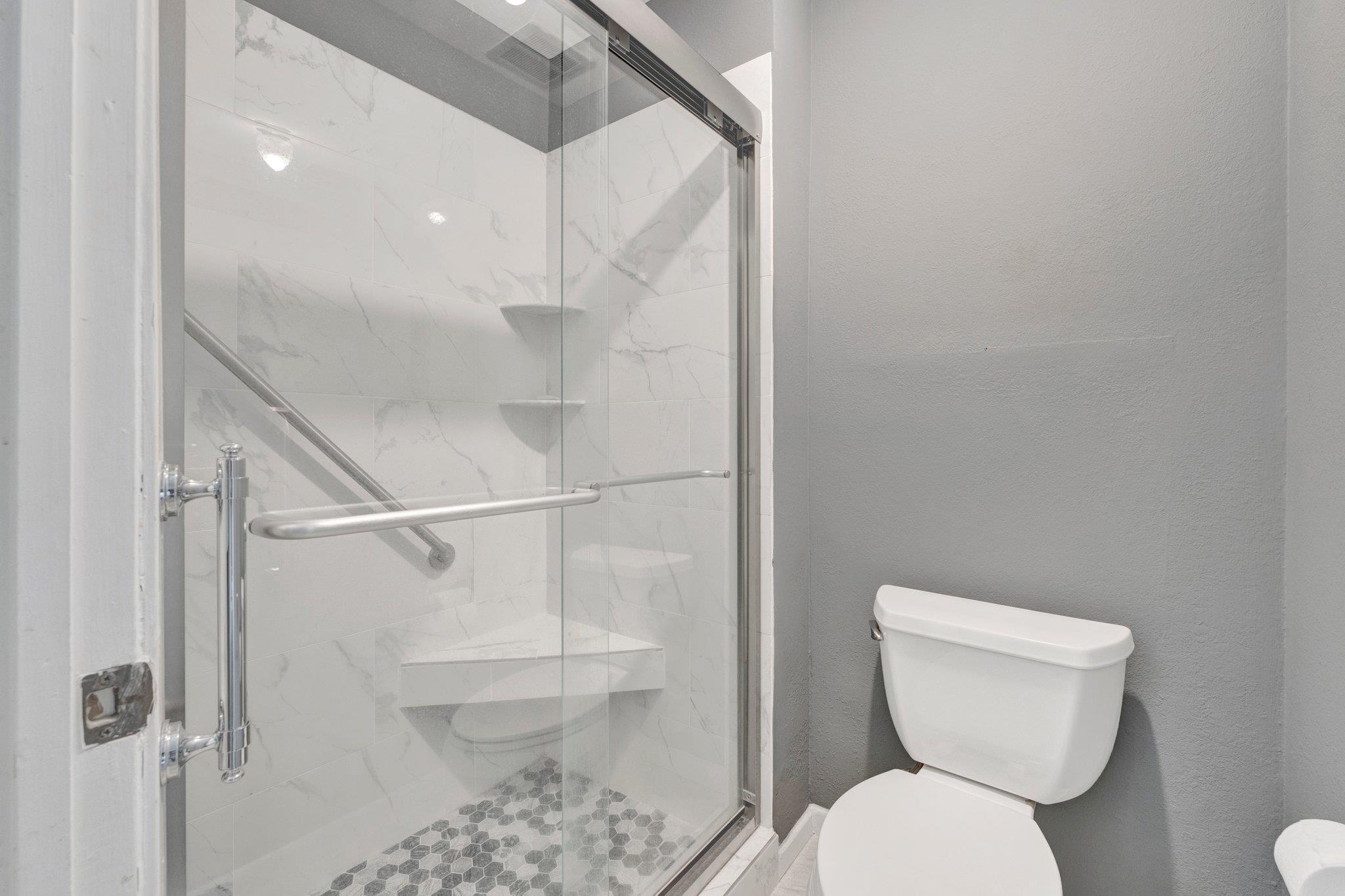 Bathroom with toilet and an enclosed, updated shower