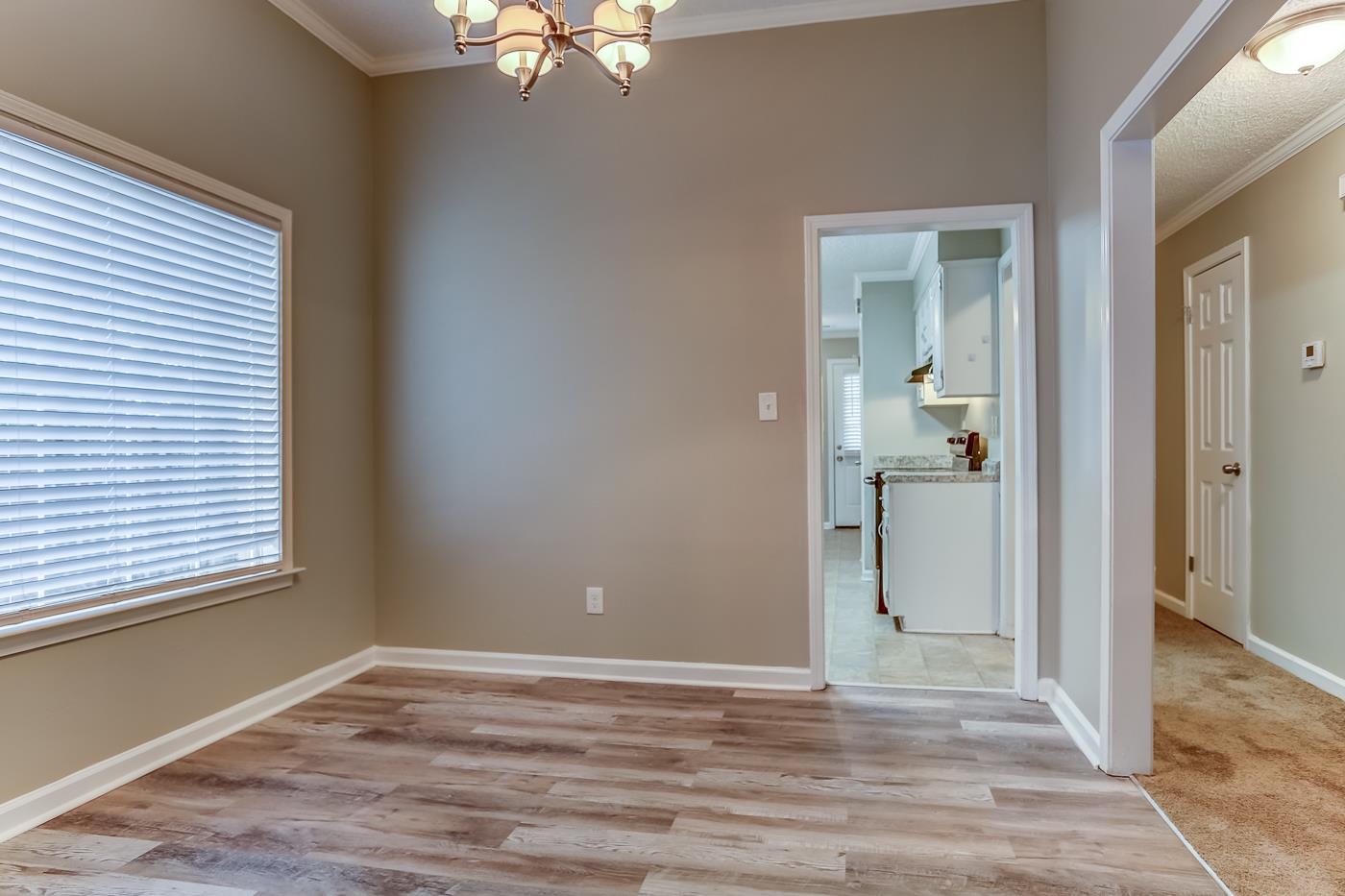 Empty room featuring a chandelier, light hardwood / wood-style flooring, and ornamental molding