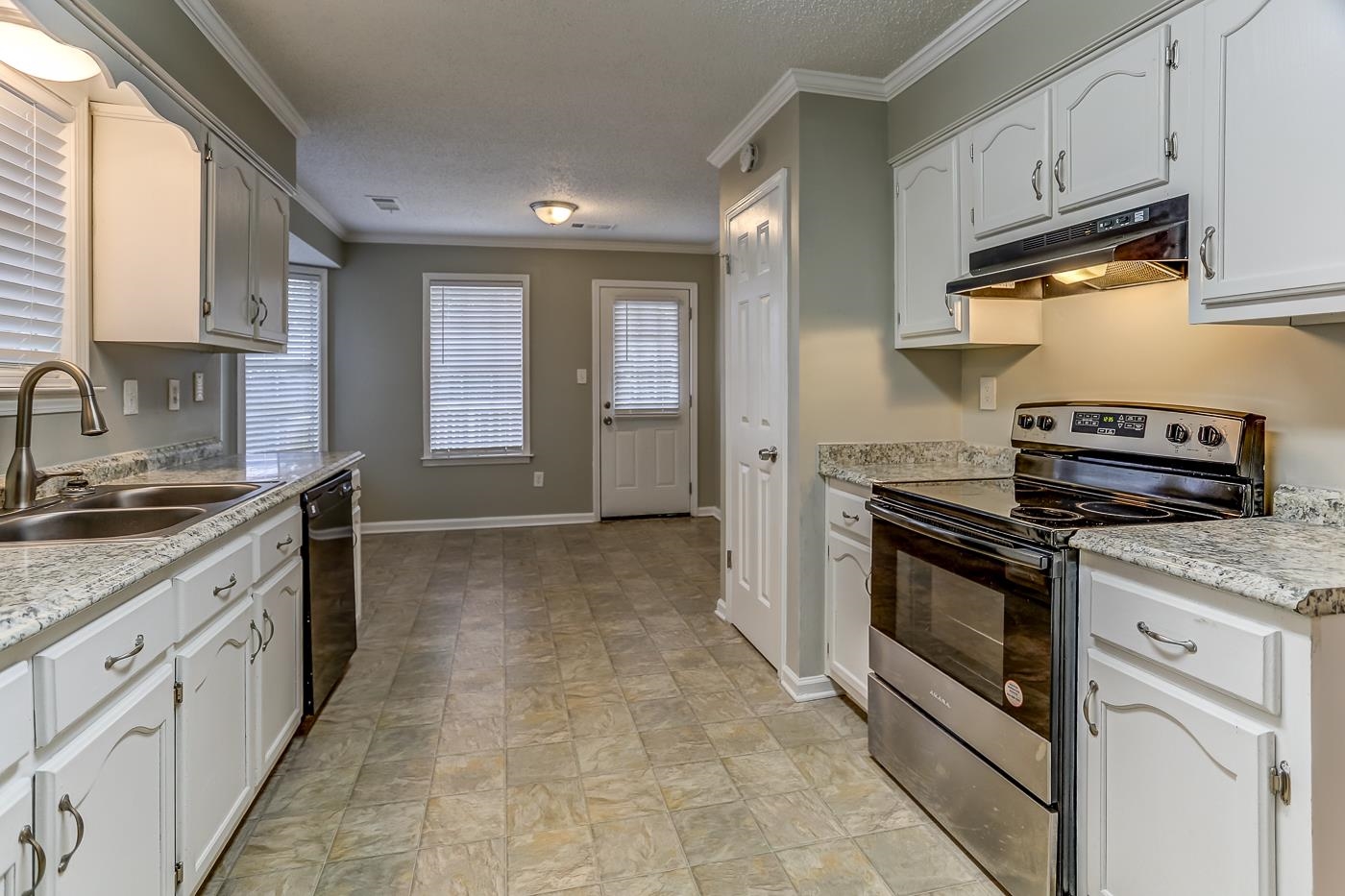 Kitchen with ornamental molding, black dishwasher, sink, white cabinets, and electric range