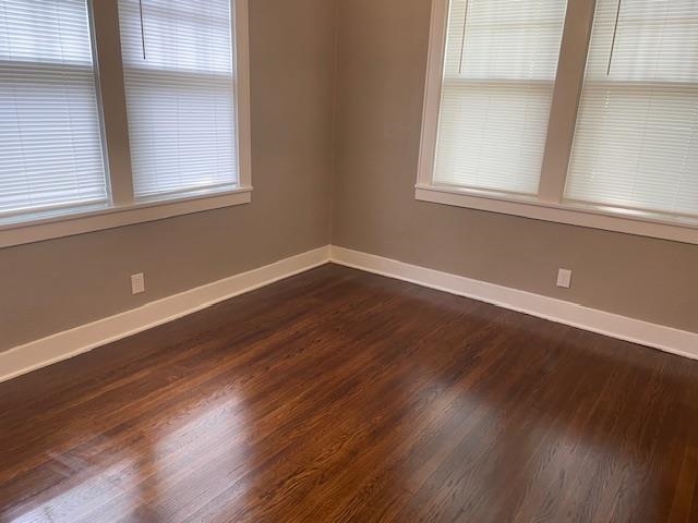 Unfurnished room featuring a healthy amount of sunlight and dark hardwood / wood-style floors