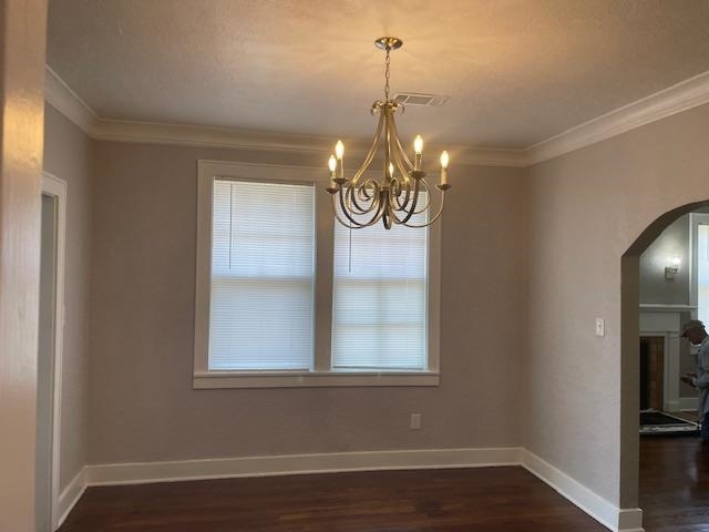 Unfurnished dining area with ornamental molding, dark hardwood / wood-style floors, and an inviting chandelier