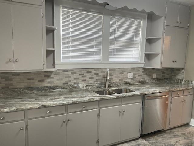 Kitchen with dishwasher, light stone counters, sink, and tasteful backsplash