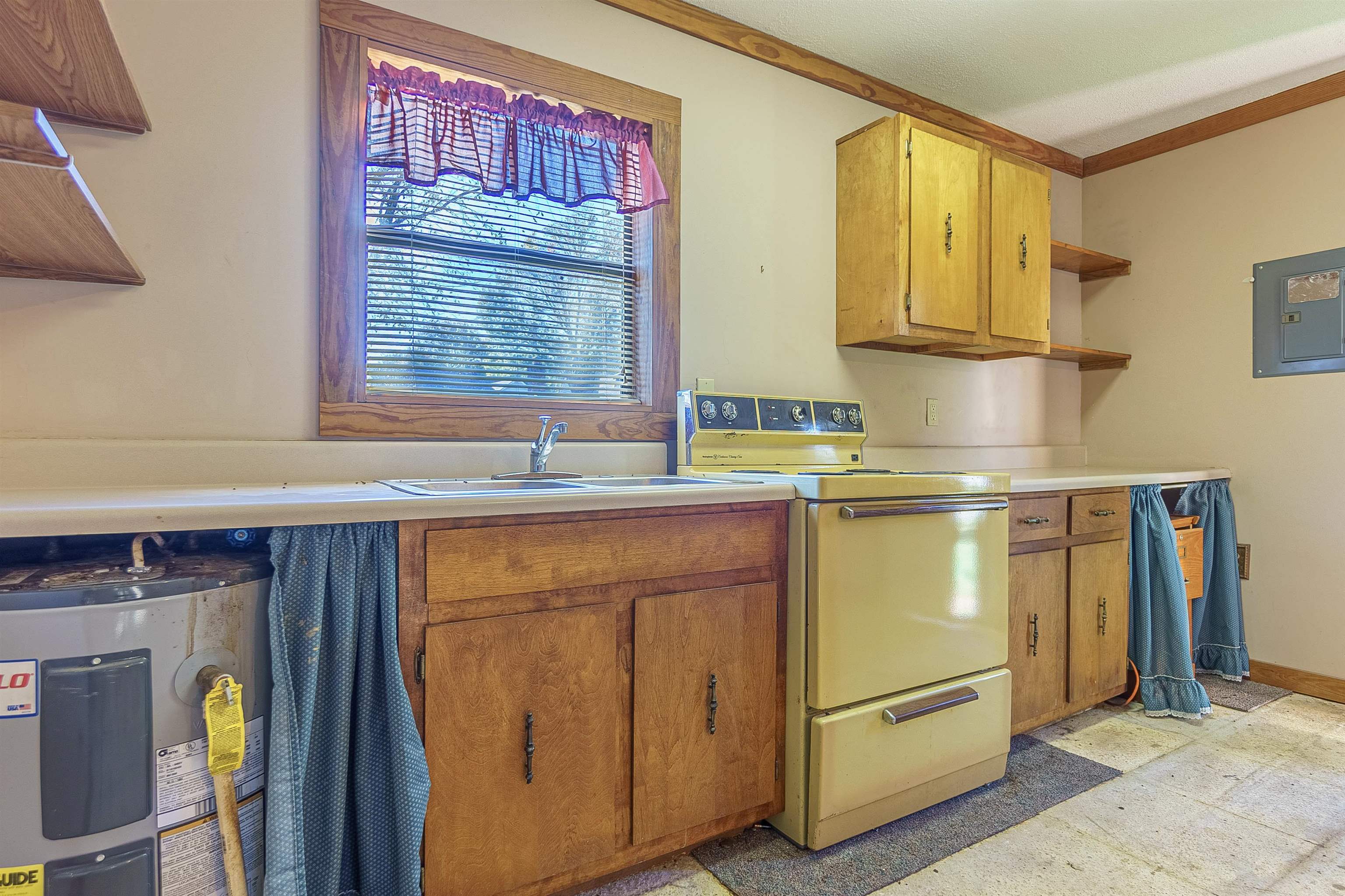 Kitchen featuring electric panel, water heater, sink, and white stove